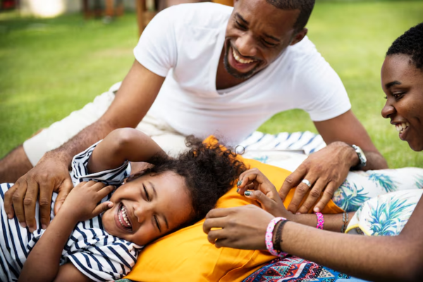 Joyful Black family spending quality time together in their backyard during summer, creating lasting memories and strengthening family bonds through laughter and love