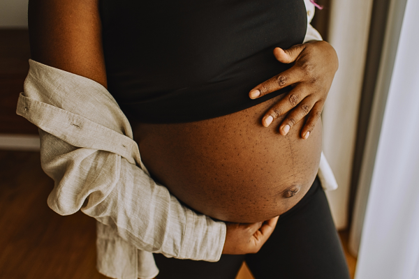 At-home pregnancy moment featuring a pregnant woman gently holding her baby bump, reflecting on her journey of getting pregnant with IUI