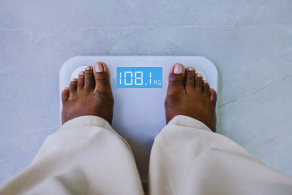 Woman standing on a digital fat scale, tracking body changes related to ovulation weight gain during her menstrual cycle